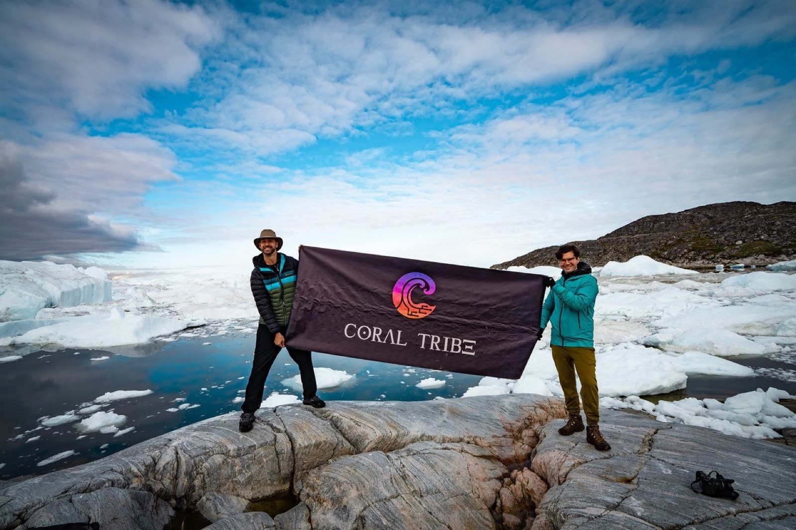 Two Tribe members holding the Coral Tribe flag on Greenland ice